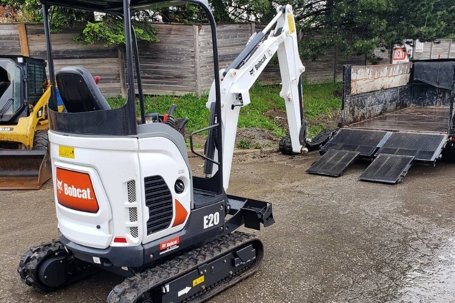 Image depicts a Bobcat E20 Excavator rental being dropped off at a customer's home